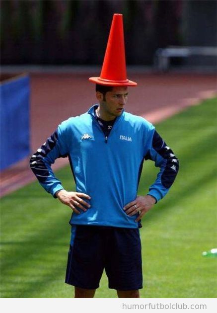 Futbolista aburrido en el entrenamiento con un cono encima de la cabeza