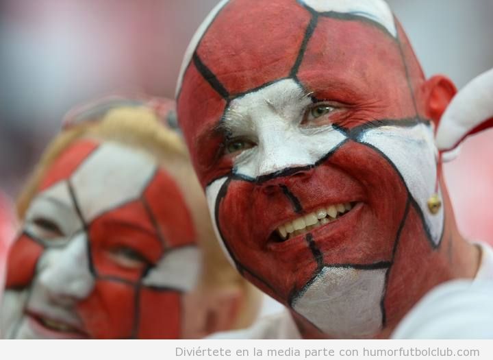 Aficionados de Polonia con la cara pintada como un balón de fútbol rojo y blanco