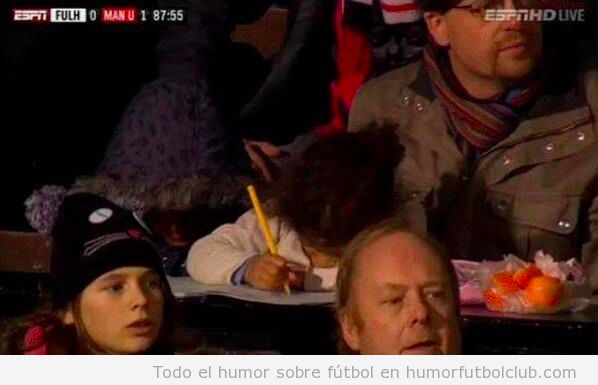 Foto graciosa de una niña haciendo los deberes en el estadio, en el partido Fulham vs Manchester United